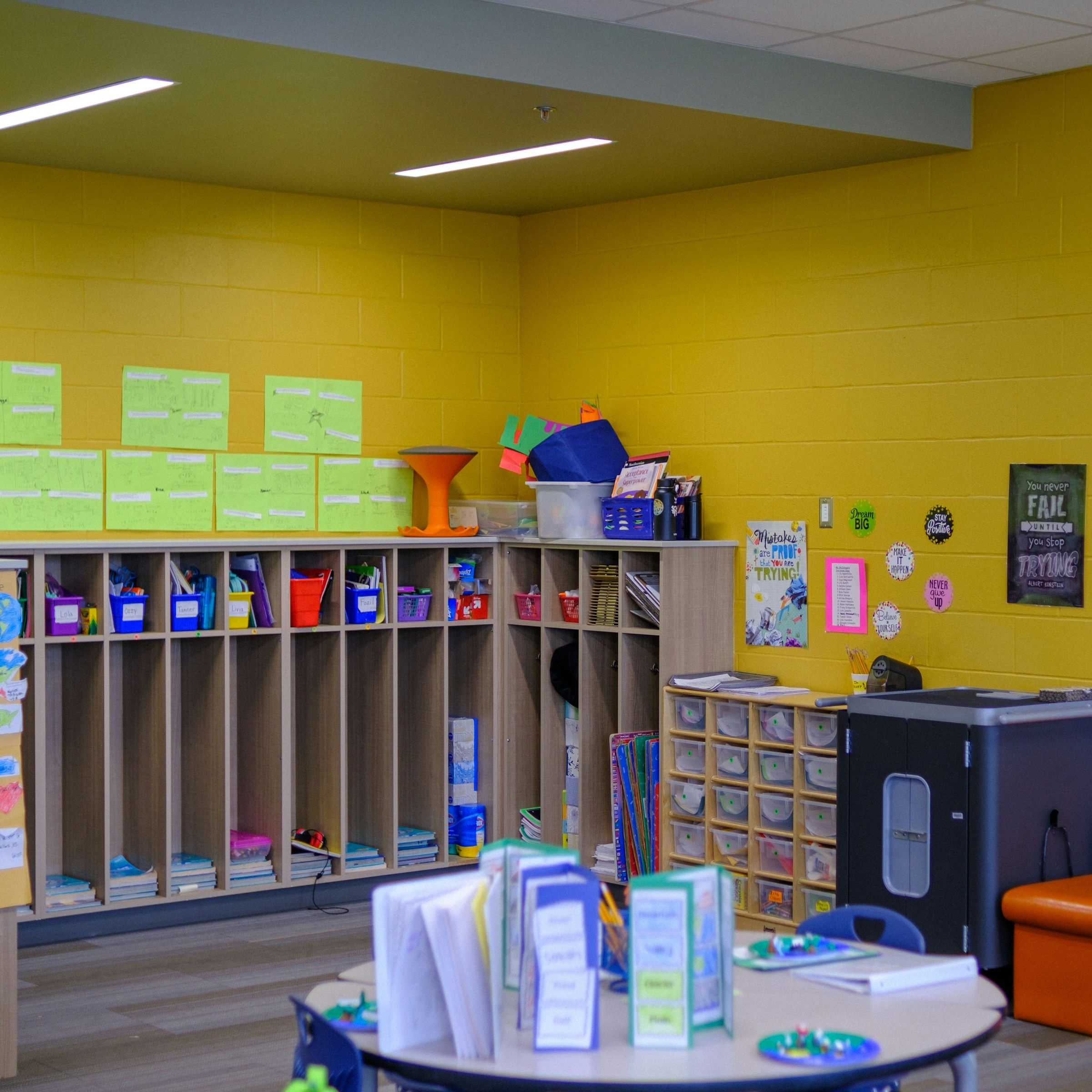 Wooden cubbies with labelled storage bins in an empty classroom