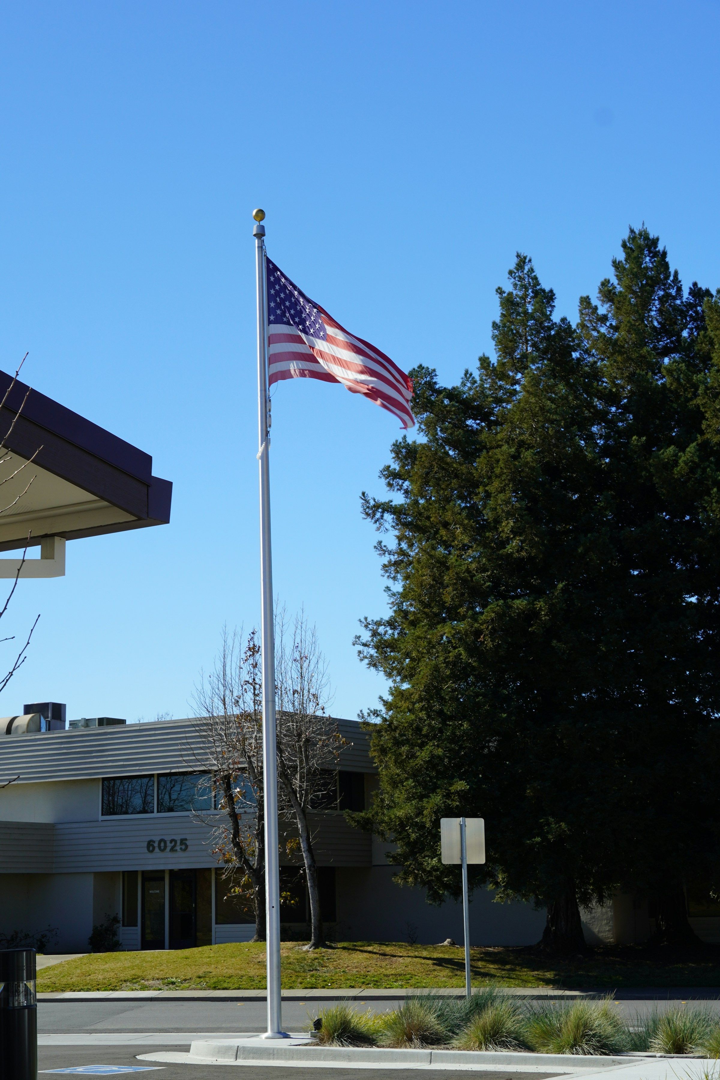 An American flag on a pole in front of a low school building